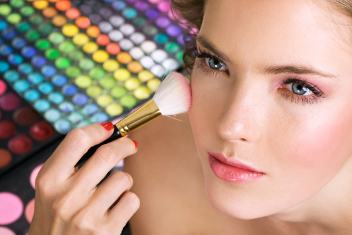 Makeup artist applying blusher on woman face