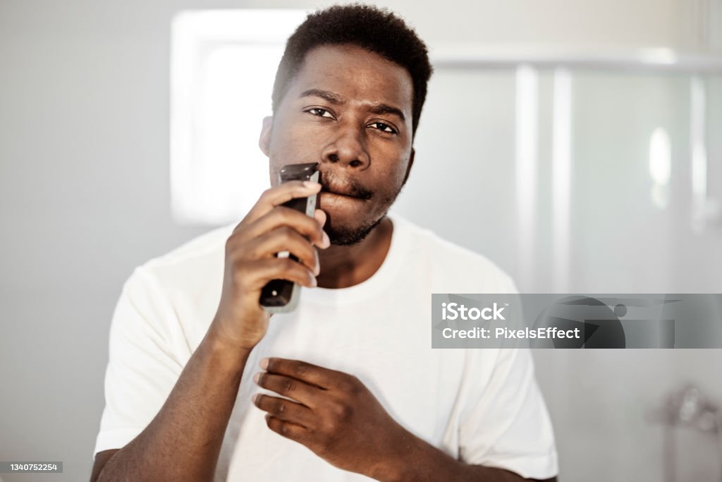 Getting ready for the day ahead Portrait of young african american man shaving with trimmer Shaving Stock Photo