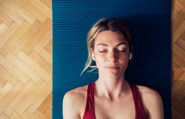 istock Woman Meditating Lying On Exercise Mat Wearing Wireless Earphones 1340753569