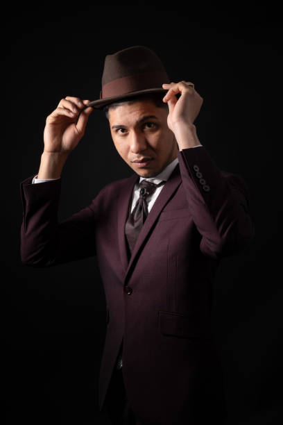 istock Latin man in suit on black background with hands on hat 1340753581