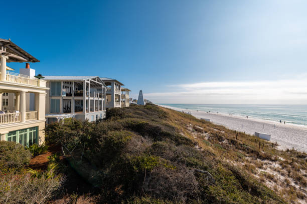 High angle view from wooden pavilion gazebo by beach at Gulf of Mexico at Seaside, Florida by new urbanism rental house home architecture with people walking on ocean sea coast High angle view from wooden pavilion gazebo by beach at Gulf of Mexico at Seaside, Florida by new urbanism rental house home architecture with people walking on ocean sea coast beach house stock pictures, royalty-free photos & images