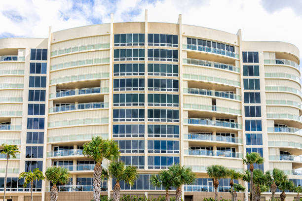 Beachfront waterfront condo condominium apartment complex on shore coast of Vanderbilt beach in Naples, Florida with modern balconies, windows and ocean Gulf of Mexico view