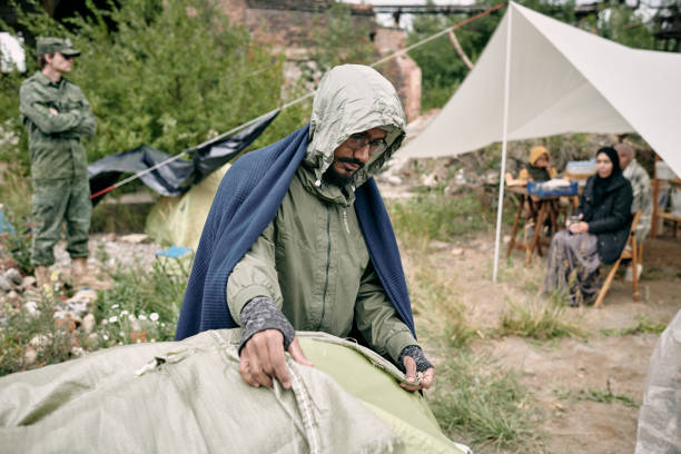 istock Refugee Man Covering Tent With Sack 1340755350