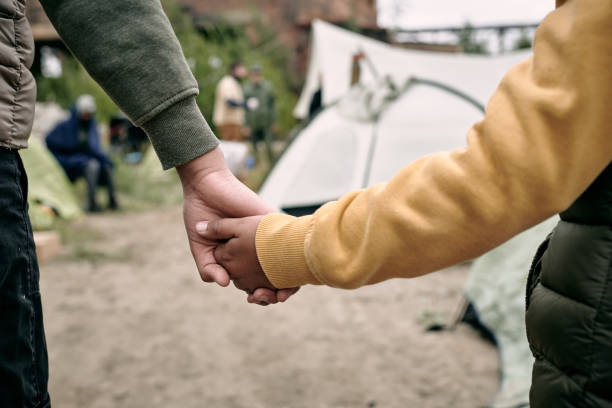 Children Coming In To Migrant Camp Rear view of unrecognizable children of different ages holding hands while coming in to migrant camp refugee camp stock pictures, royalty-free photos & images
