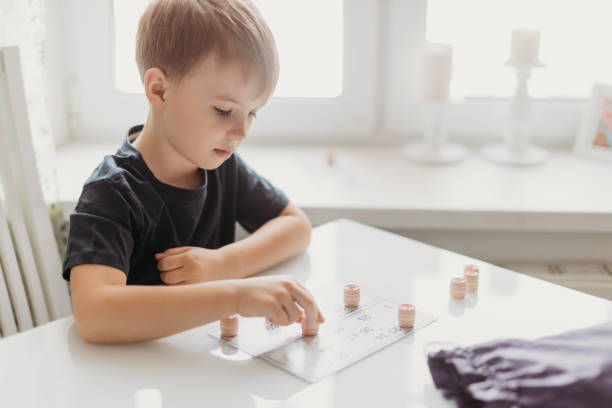 istock a lotto game. A boy child is playing a lotto game at a white table on a light background. 1340758745