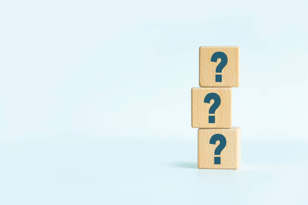 istock Three wooden cube block shapes with question mark symbol against light blue background with copyspace 1340758909