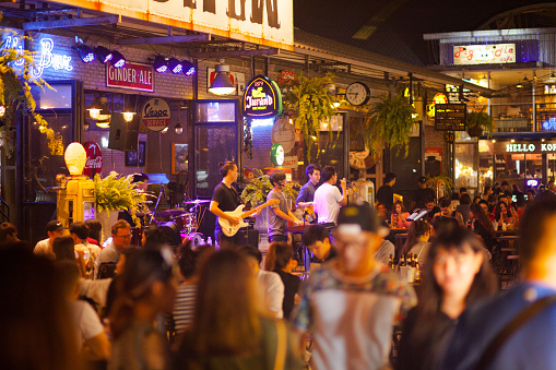 Crowded bar and thai music band on night market Esplanade in Bangkok. Daily nightlife scene on popular night market. There are many young thai people and tourists. Night market was closed and shut down in August 2021 in covid era.