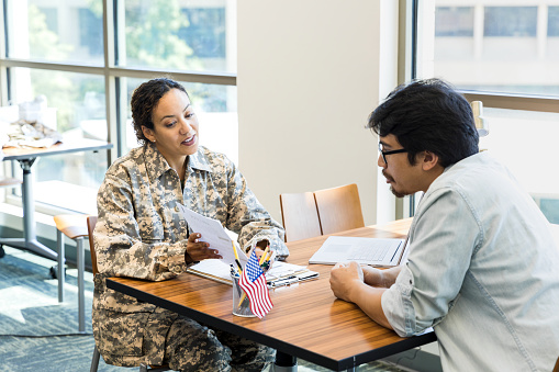At the family services office, the mid adult female soldier explains the documents to the mid adult man.