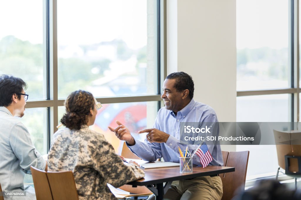 Female soldier and husband meet with mature male loan officer The unrecognizable mid adult female soldier and her mid adult husband meet with the mature adult male loan officer at the credit union. Veteran Stock Photo