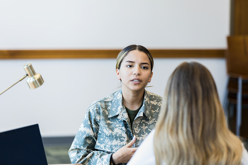 Young woman talks with military recruiter in office