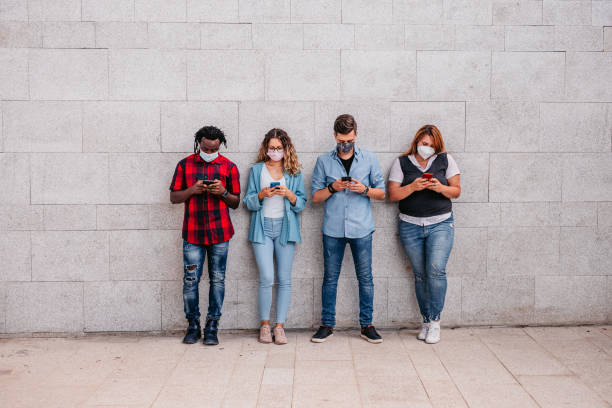 istock Four young people using phones next to each other 1340764008