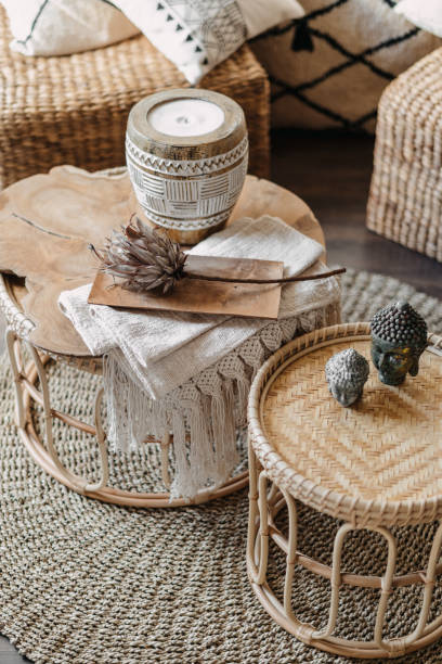 Wicker furniture with home decor in bright living room High angle view of home decor, wicker furniture with natural materials stand in bright living room interior at bohemian style. Vertical shot of bamboo table, candle and dry flower in cozy apartment coffee table top stock pictures, royalty-free photos & images