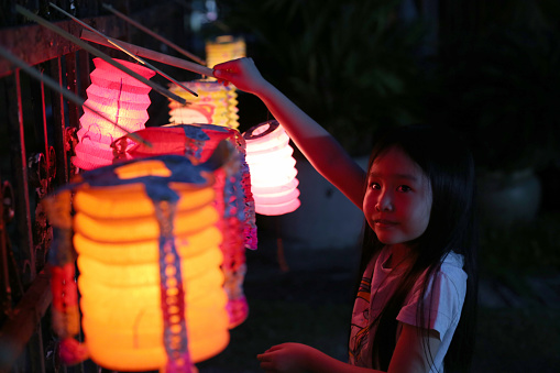 An Asian girl is enjoying playing with Chinese lantern for joyous celebration.