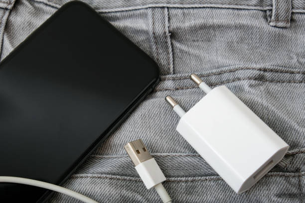 ładowarka usb, wtyczka przewodu i adaptera oraz smartfon w szarej kieszeni dżinsów, nie zapomnij o ładowarce w domu - plug adapter charging mobile phone battery charger zdjęcia i obrazy z banku zdjęć