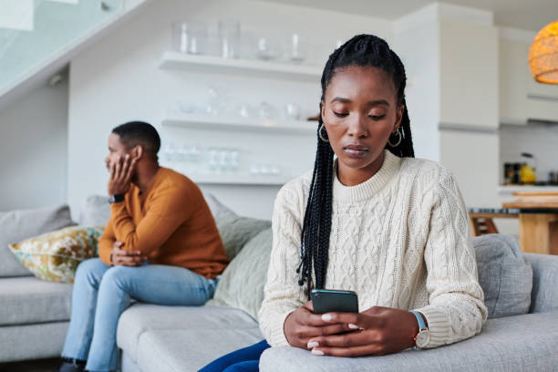 foto de una joven ignorando a su pareja mientras usaba un teléfono celular en casa - african descent addiction african ethnicity rudeness fotografías e imágenes de stock