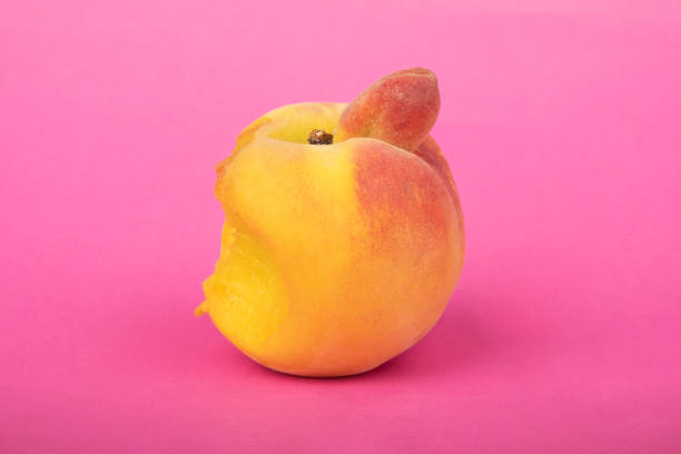 bit off intimacy peach, fruit with sexual connotations on pink background stock photo
