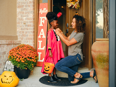A mother prepares a child’s costume before going out trick or treating on Halloween.