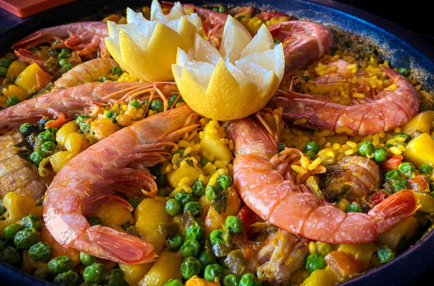 istock Chef cooking a paella bubbling with prawns, lemon and assorted seafood. 1340775941