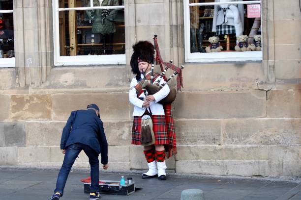 Man playing bagpipes in the street dressed in traditional Scottish dress