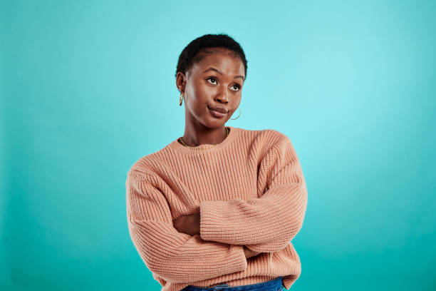 plan d’une femme debout, les bras croisés sur un fond turquoise - irritation photos et images de collection