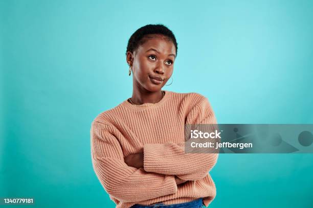 Shot Of A Woman Standing With Her Arms Crossed Against A Turquoise Background Stock Photo - Download Image Now