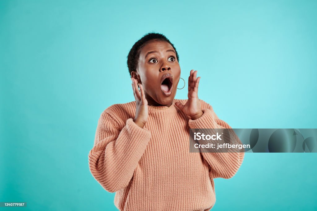 Shot of a young woman looking surprised while standing against a turquoise background This is what we've been waiting for! Surprise Stock Photo