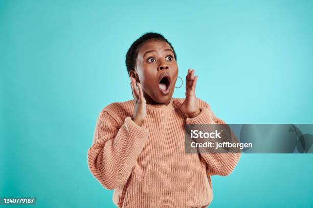 Shot Of A Young Woman Looking Surprised While Standing Against A Turquoise Background Stock Photo - Download Image Now
