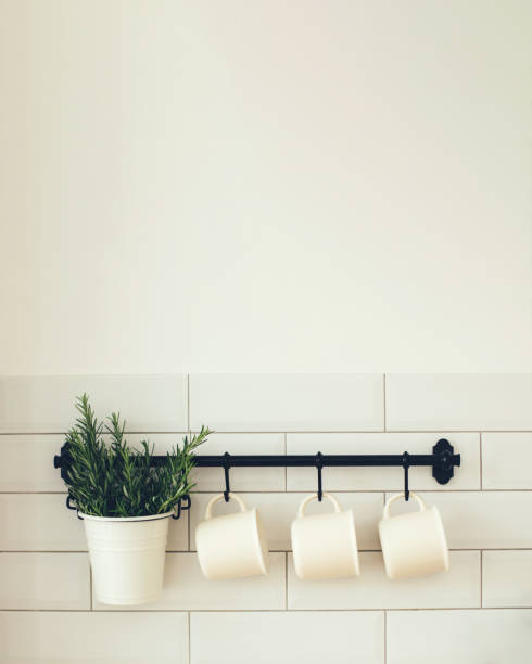 istock Kitchen interior with white wall and black rail with coffee mug and vase with fresh green rosemary 1340779778