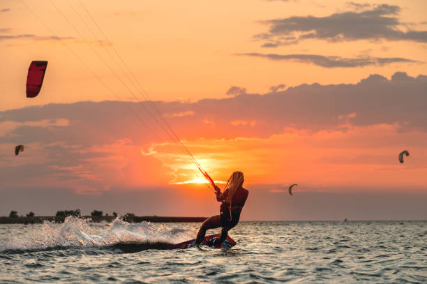 Young woman professional kiter performs ride beautiful background of the sunset and sea stock photo