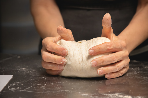 close-up of female hands kneading dough for making artisan bread at home bakery.
