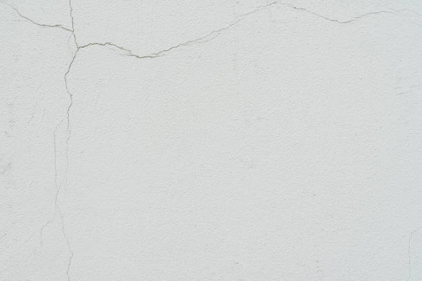 istock Concrete wall with cracks, texture of ruined plaster, light gray color. Background 1340782673