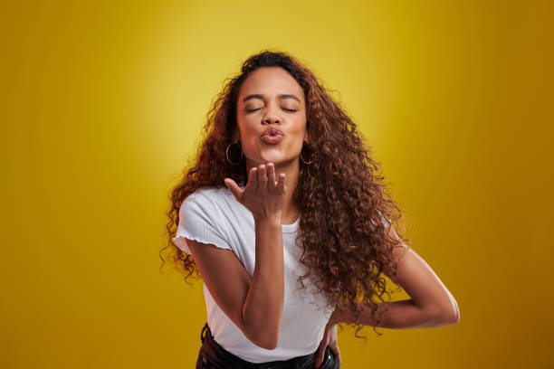 Studio portrait of a young woman blowing a kiss against a yellow background I just wanted to say... mwah! blowing a kiss stock pictures, royalty-free photos & images