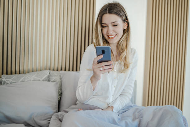 istock Young woman uses a mobile phone in bed 1340787945