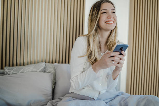 istock Young woman uses a mobile phone in bed 1340788002