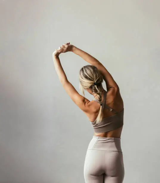 A portrait of a young blonde Caucasian woman stretching her back from behind