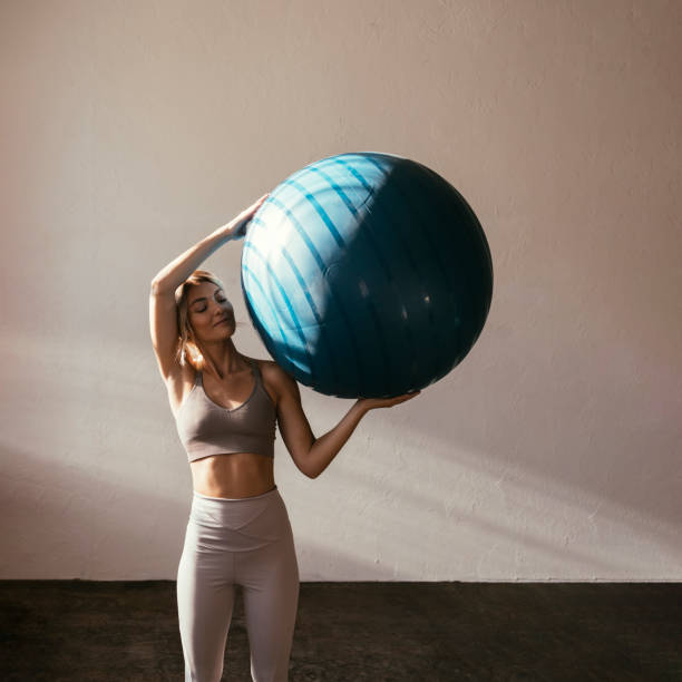 une jeune femme blonde caucasienne tenant un ballon de yoga - yoga ball photos et images de collection