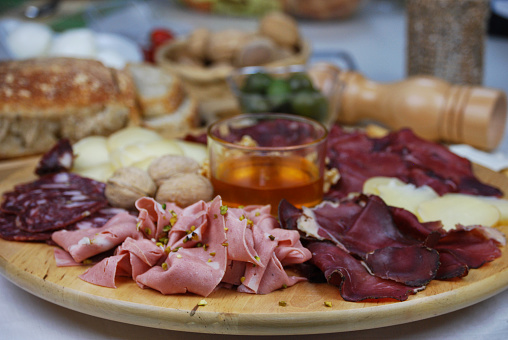 Platter of cold cuts and cheeses with honey in the center