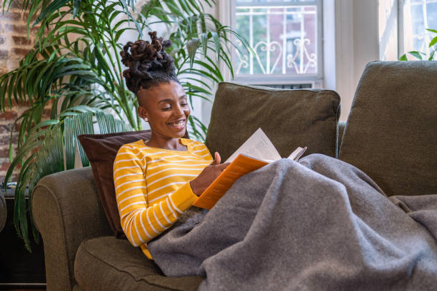 istock Black woman reading a book and relaxing on the couch 1340801561