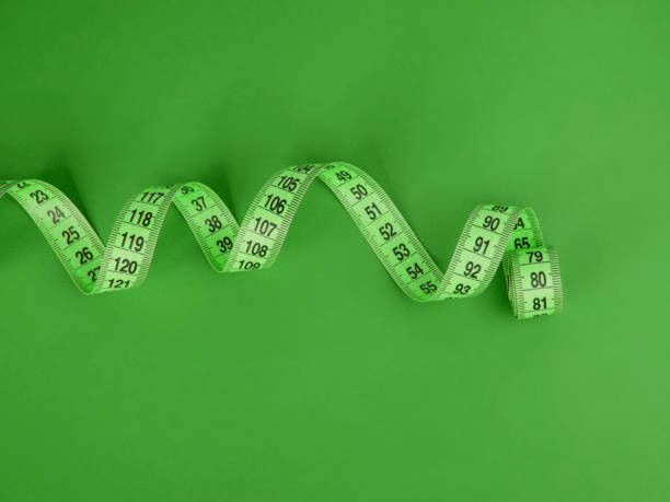 istock Green tape measure on the green background 1340803079