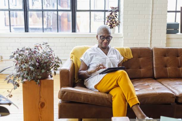 istock Senior businesswoman working on tablet computer from sofa at home 1340809254