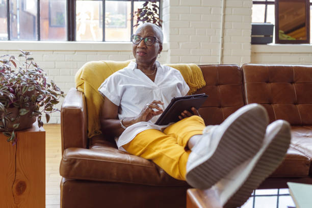 istock Senior businesswoman working on tablet computer from sofa at home 1340809275