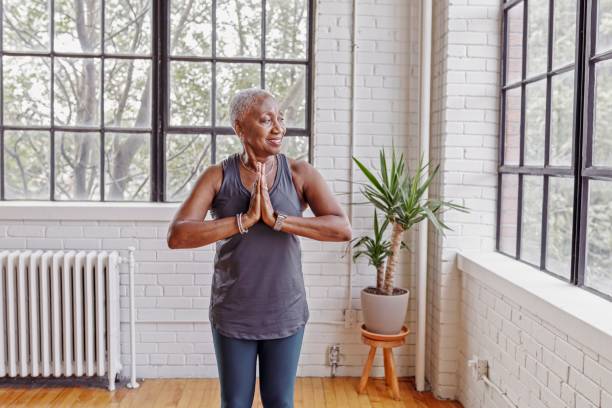 istock Active senior woman doing yoga at home 1340809407