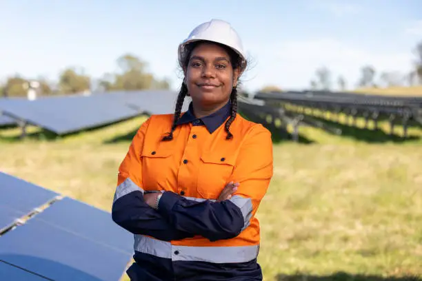 Portrait Of Female Aboriginal Australian Worker On Solar Farm wearing Hi-Vis Workwear