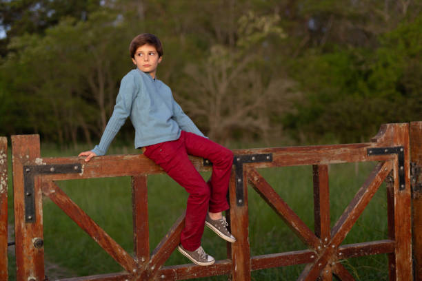 istock 10 years old boy sitting at gate at sunset 1340820294