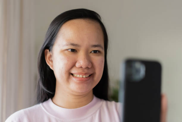 istock Asian woman using mobile phone for video calling with her smile 1340821409