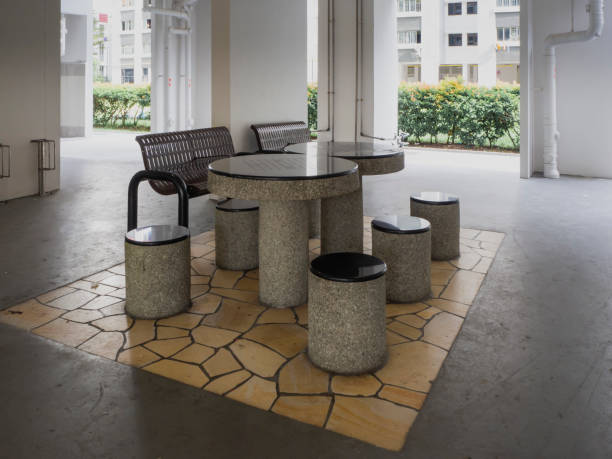 Clean HDB void deck area with a benches, stools and tables for residents to rest and relax
