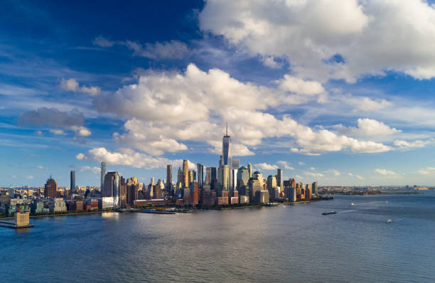 Lower Manhattan Skyline With Blue Sky And Puffy Clouds Lower Manhattan (Downtown New York City) elevated skyline view during the late afternoon with the Hudson River in the foreground and a deep blue sky with puffy cumulus clouds in the background. lower manhattan stock pictures, royalty-free photos & images