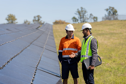 Indian-Australian Engineer and Aboriginal Australian Apprentice Working Together On Solar Farm Installation