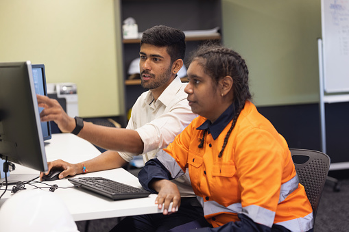 Indian-Australian Engineer and Aboriginal Australian Apprentice Working Together In The Office On Solar Farm Technology
