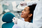 Happy African American woman during appointment at dentist office.